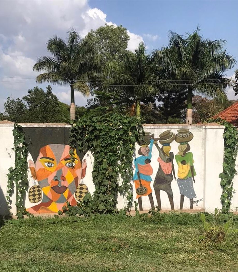 A vibrant mural on a wall in Lira, Uganda, depicting African women carrying goods on their heads — painted street art representing the strength and resilience of Northern Ugandan women