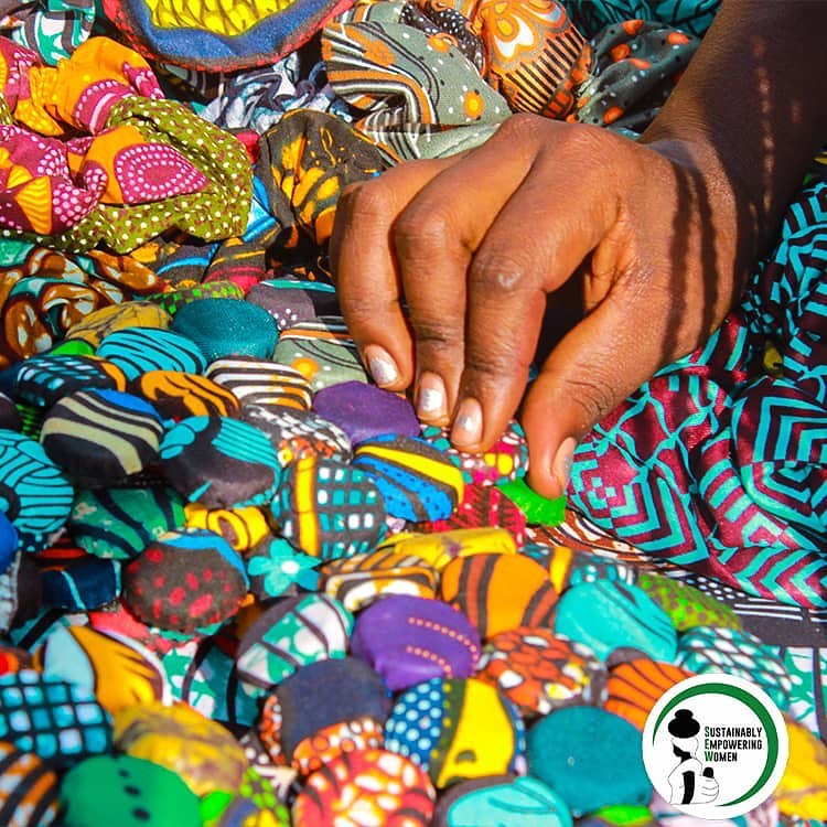 Colourful handmade fabric sanitary pads made by SEW women, laid out in vibrant African prints — sustainable menstrual health products distributed as part of the programme